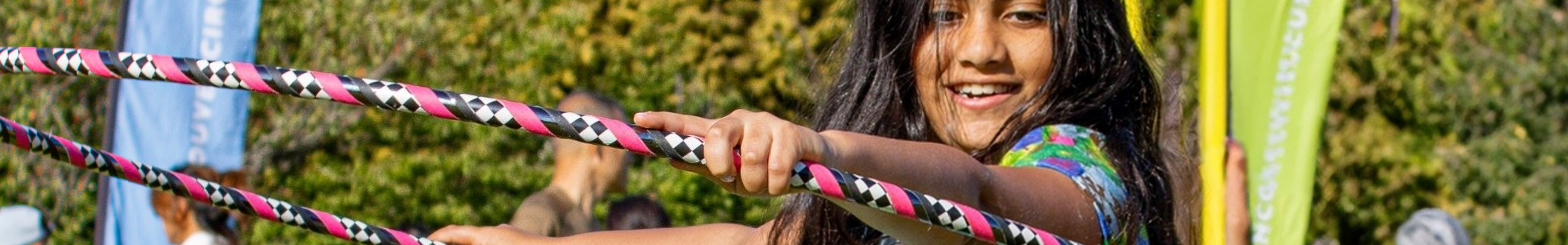 A young girl holding a hula hoop in her hand.