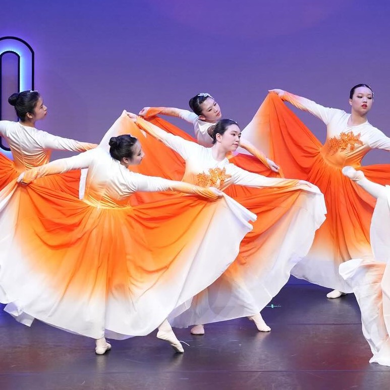 The image shows a group of people dancing Chinese dance, ranging from beginner to advanced levels. They are dressed in traditional Chinese dance clothing and are performing choreographed movements. The activity captures the essence of modern dance and performance art.