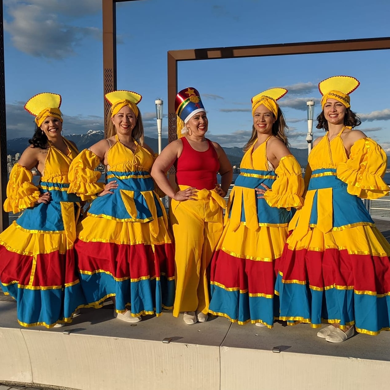 The image features a group of women wearing colorful dresses. They are part of a Brazilian Swag dance group, showcasing their vibrant attire and possibly performing a dance routine outdoors. The women seem to be happy and smiling while engaging in the dance activity.