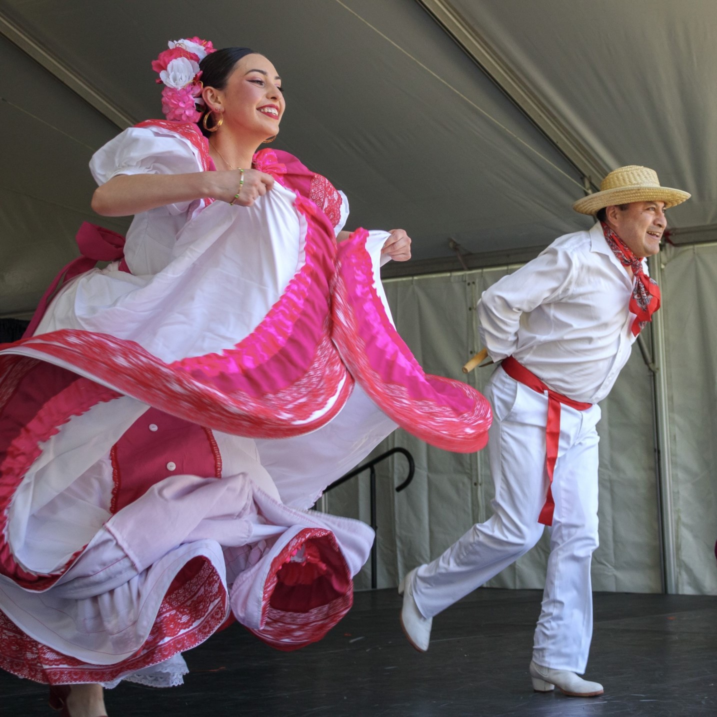 The image depicts a man and woman dancing in a Mexico Vivo Folklore setting. They are dressed in traditional costumes and are engaging in a dance performance. 