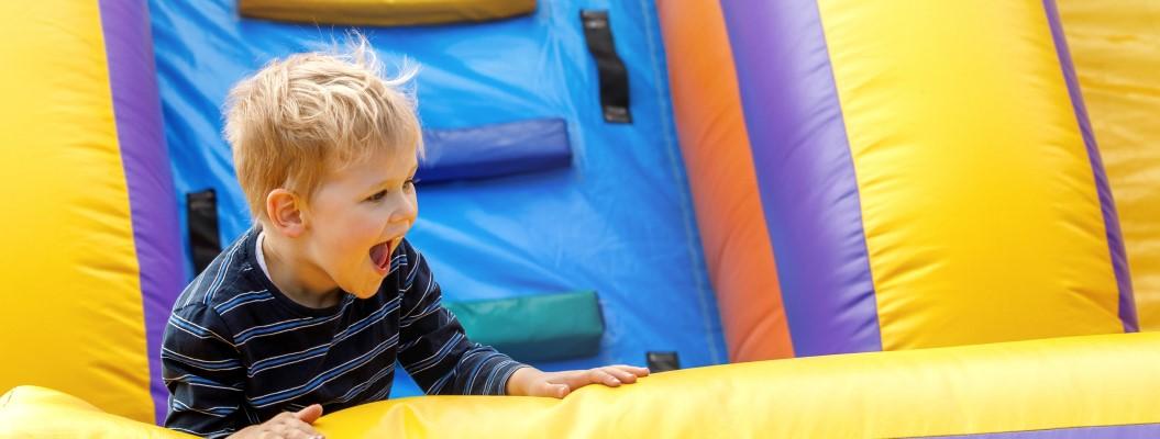 The image is of a boy playing on a slide. The boy is wearing blue clothing and appears to be at an indoor play area.