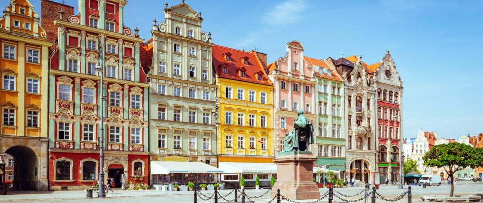 The photo is of a statue in front of a building in Wroclaw, Poland. The building appears to be historic tenements on the main square.