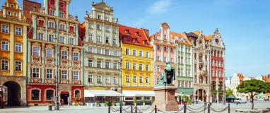 The photo is of a statue in front of a building in Wroclaw, Poland. The building appears to be historic tenements on the main square.